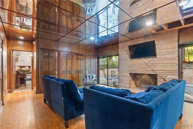living room featuring wooden walls, a fireplace, and a towering ceiling