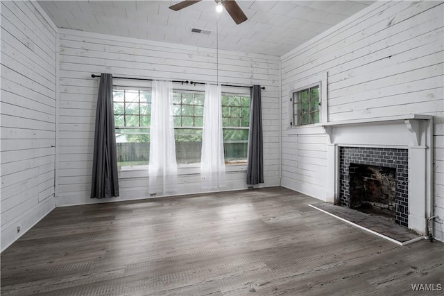 221 3rd Ct SW, Fayette, AL 35555 - unfurnished living room featuring ceiling fan, wood walls, a tiled fireplace, and wood finished floors
