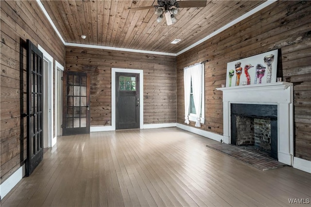 221 3rd Ct SW, Fayette, AL 35555 - unfurnished living room featuring hardwood / wood-style floors, a fireplace with raised hearth, a ceiling fan, wooden ceiling, and wooden walls