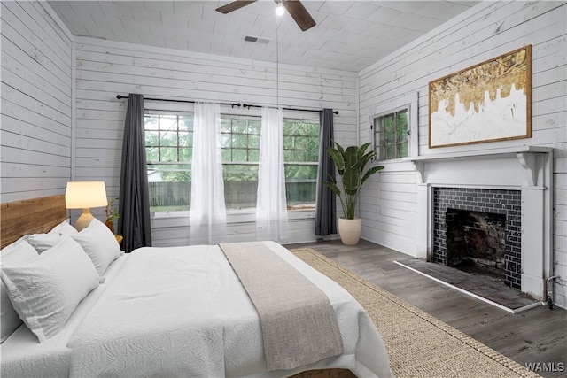 221 3rd Ct SW, Fayette, AL 35555 - bedroom featuring wood finished floors, wooden walls, a fireplace, and a ceiling fan