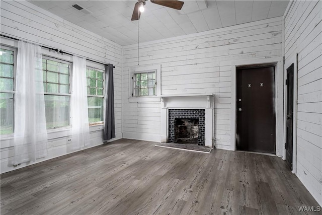 221 3rd Ct SW, Fayette, AL 35555 - unfurnished living room featuring wood finished floors, a ceiling fan, a fireplace with raised hearth, and wooden walls