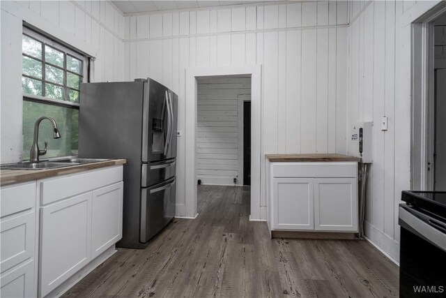 221 3rd Ct SW, Fayette, AL 35555 - kitchen with stainless steel fridge with ice dispenser, butcher block countertops, dark wood finished floors, white cabinetry, and wooden walls