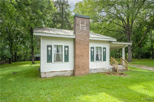 221 3rd Ct SW, Fayette, AL 35555 - view of home's exterior featuring a chimney, a yard, a metal roof, and view of scattered trees