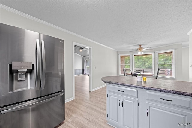kitchen with light wood finished floors, a ceiling fan, a textured ceiling, and stainless steel fridge with ice dispenser