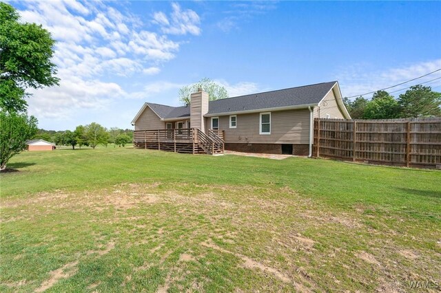 rear view of property featuring a yard, a chimney, fence, and a deck