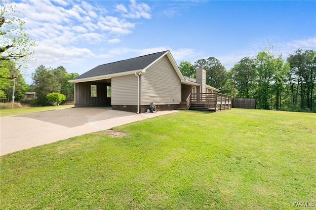 view of side of property with a yard, driveway, a chimney, and an attached carport