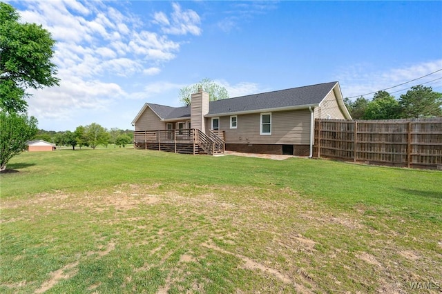 rear view of house featuring a wooden deck, a lawn, a chimney, and fence