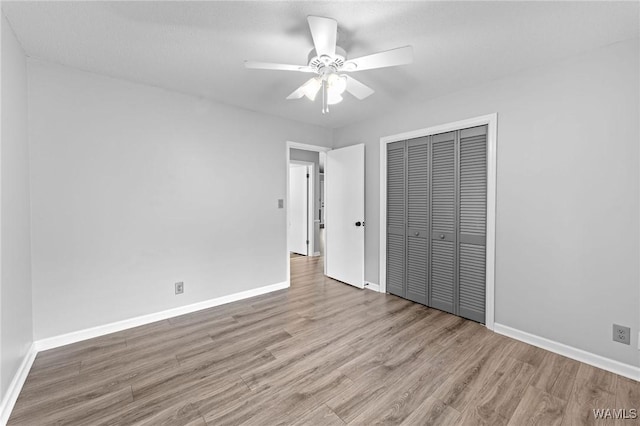 unfurnished bedroom featuring wood finished floors, a closet, baseboards, and ceiling fan