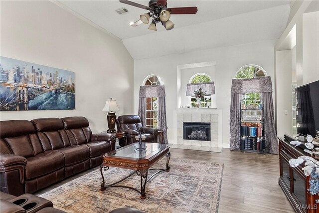 living room featuring a tiled fireplace, ceiling fan, high vaulted ceiling, and wood-type flooring