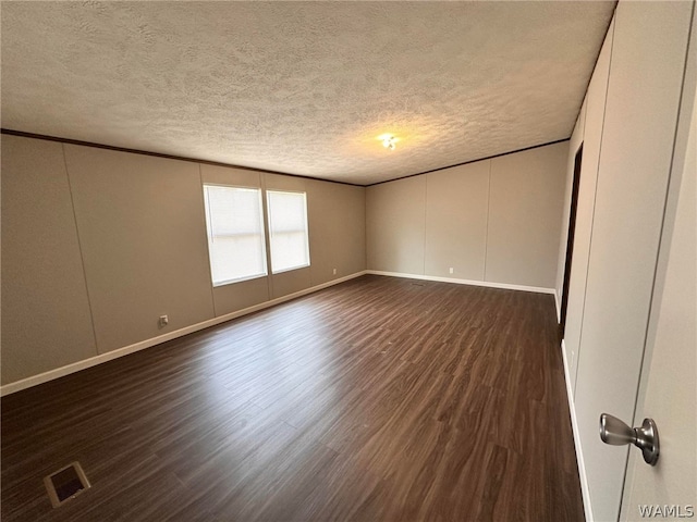 empty room featuring dark hardwood / wood-style flooring and a textured ceiling