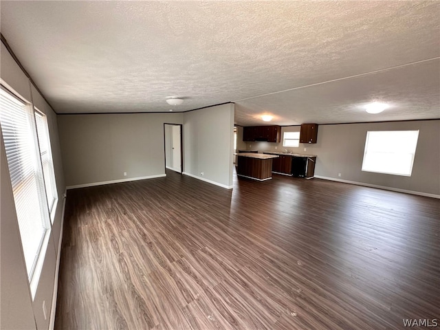 unfurnished living room featuring a textured ceiling, dark hardwood / wood-style floors, and sink