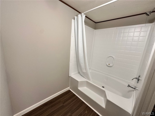 bathroom with hardwood / wood-style flooring, shower / bath combination with curtain, and a textured ceiling