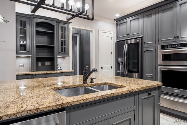 kitchen featuring light stone countertops, stainless steel appliances, gray cabinets, and sink