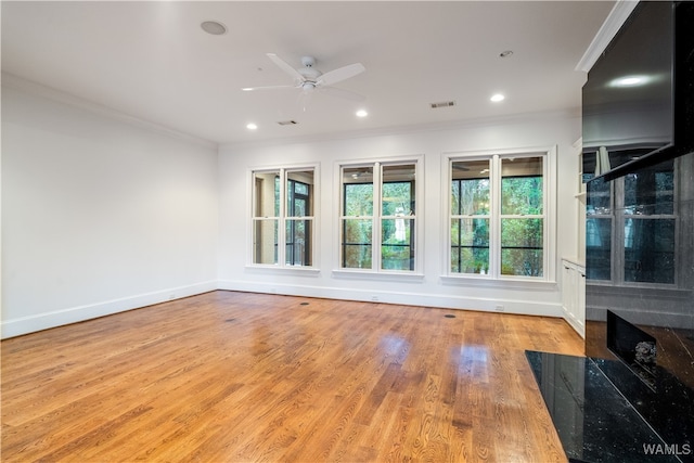 spare room featuring ceiling fan, a high end fireplace, ornamental molding, and light wood-type flooring