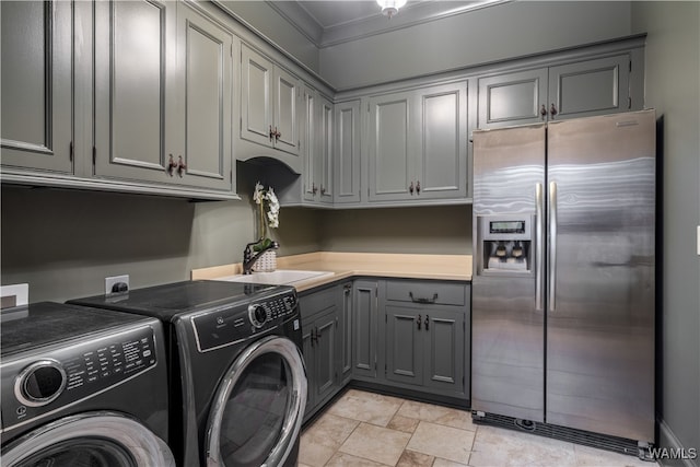 washroom with cabinets, separate washer and dryer, ornamental molding, and sink