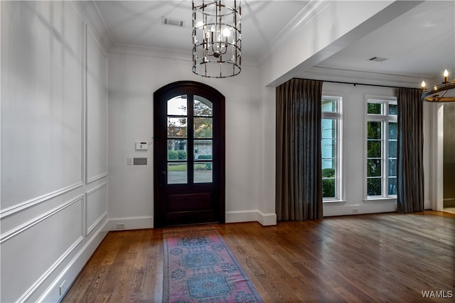 entryway featuring an inviting chandelier, crown molding, and dark wood-type flooring