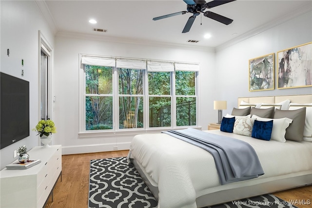 bedroom with light hardwood / wood-style floors, ceiling fan, and crown molding