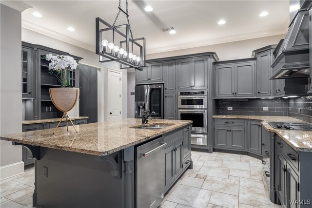 kitchen with gray cabinets, a breakfast bar, an island with sink, and appliances with stainless steel finishes