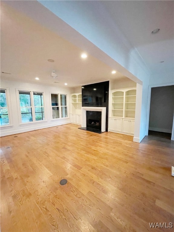 unfurnished living room with light wood-type flooring and built in features