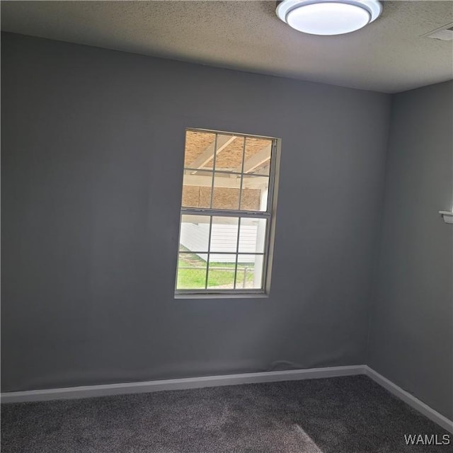carpeted empty room with baseboards, visible vents, and a textured ceiling