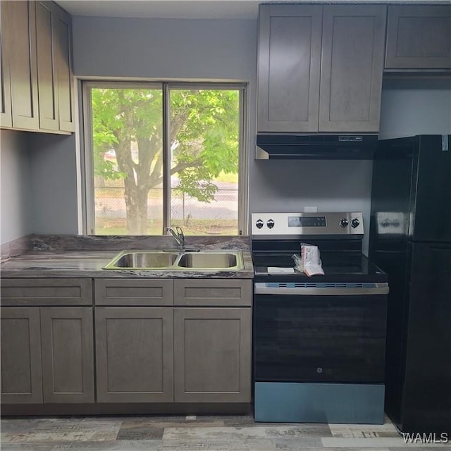 kitchen featuring stainless steel range with electric cooktop, under cabinet range hood, gray cabinets, a sink, and freestanding refrigerator