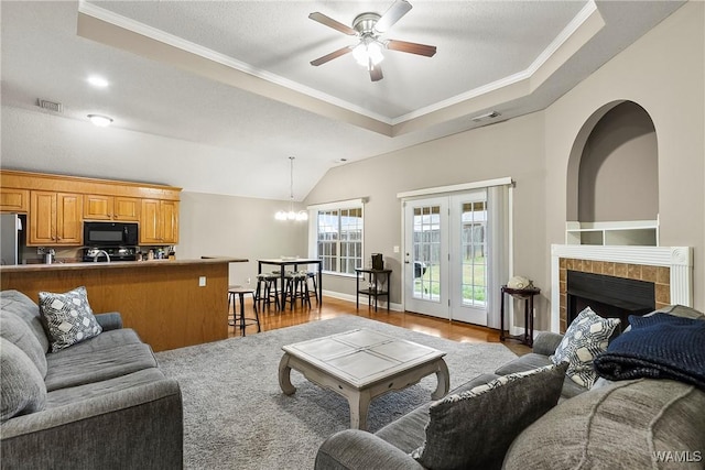 living area with a tiled fireplace, visible vents, ornamental molding, and wood finished floors