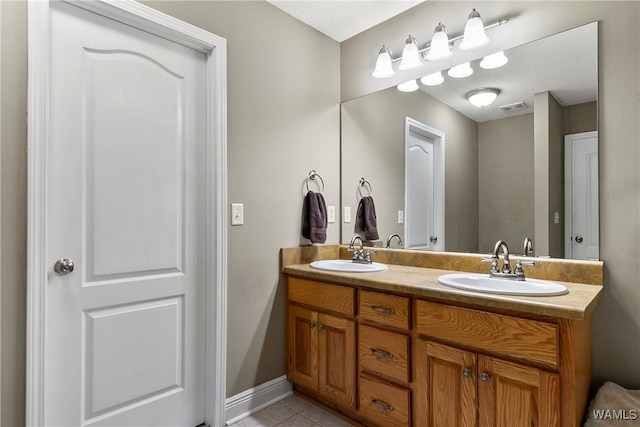 bathroom with a sink, visible vents, double vanity, and tile patterned floors