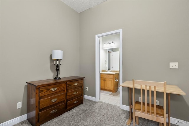 bedroom with light colored carpet, ensuite bath, baseboards, and a sink