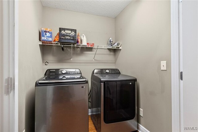 laundry area featuring washer and dryer, baseboards, a textured ceiling, and laundry area