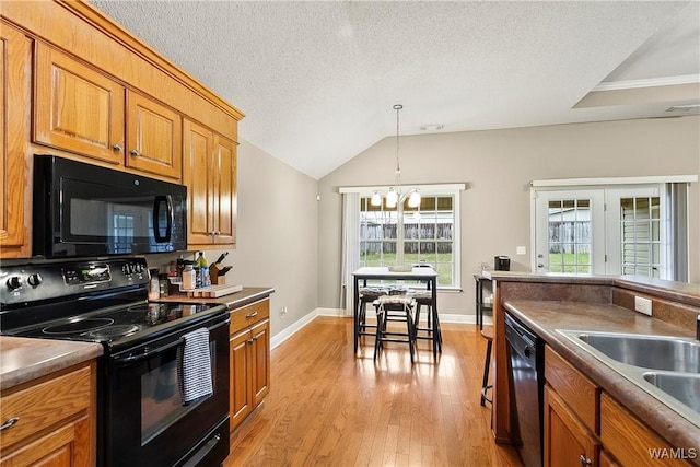 kitchen with a sink, black appliances, light wood-style flooring, and brown cabinetry