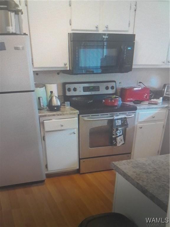 kitchen with tasteful backsplash, freestanding refrigerator, stainless steel electric range, white cabinets, and black microwave