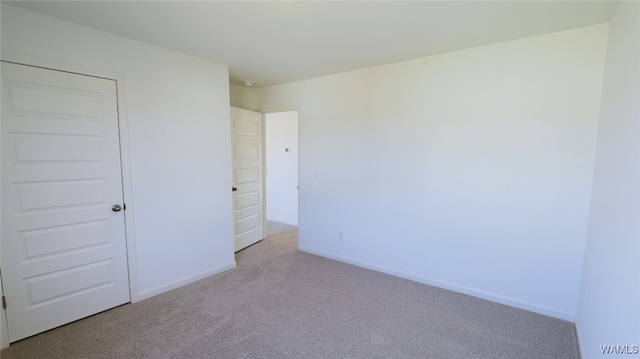 unfurnished bedroom featuring light colored carpet and a closet