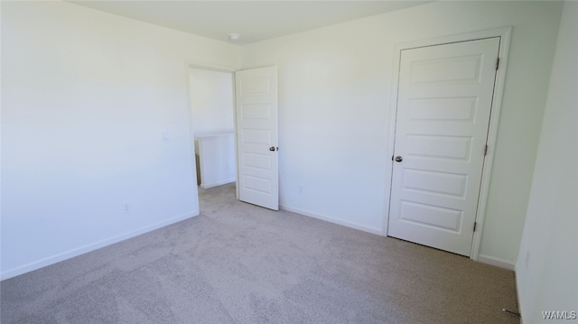 unfurnished bedroom featuring a closet and light colored carpet