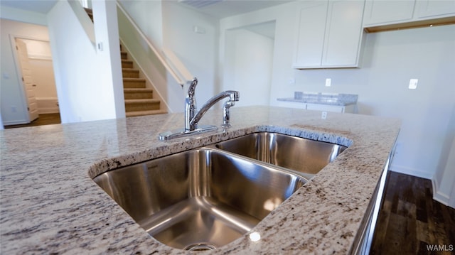 kitchen featuring white cabinetry, light stone countertops, sink, and dark wood-type flooring