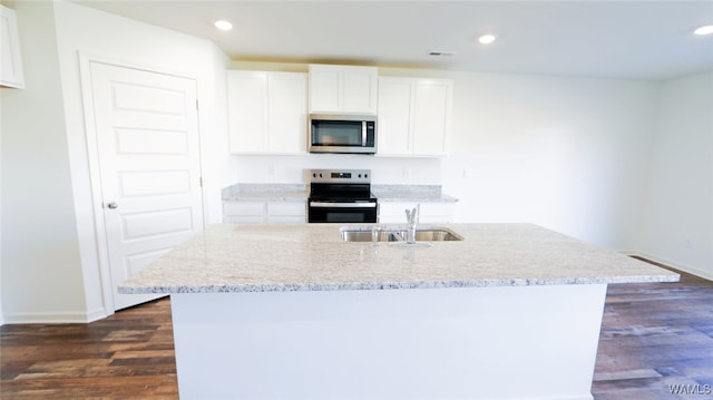 kitchen with appliances with stainless steel finishes, a kitchen island with sink, dark wood-type flooring, sink, and white cabinetry