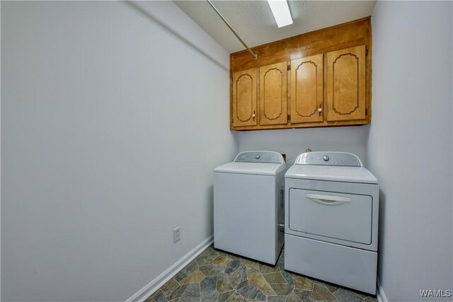 clothes washing area with washer and dryer and cabinets