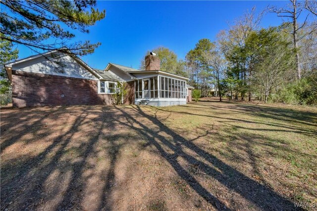 back of house featuring a lawn and a sunroom