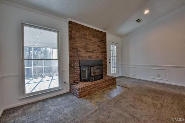 unfurnished living room with lofted ceiling, a wood stove, carpet floors, and ornamental molding