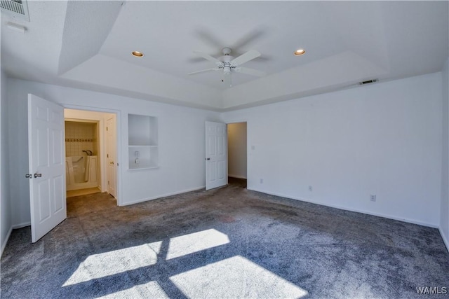 unfurnished bedroom with dark carpet, a raised ceiling, and ceiling fan