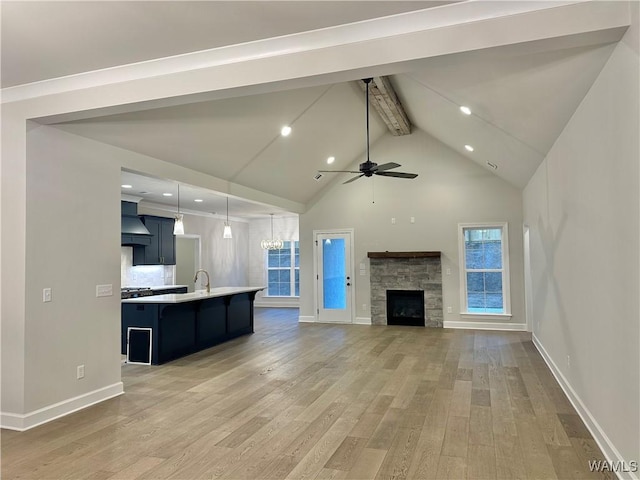 unfurnished living room with beam ceiling, ceiling fan, high vaulted ceiling, hardwood / wood-style floors, and a fireplace