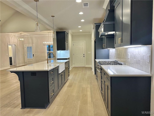 kitchen with custom exhaust hood, lofted ceiling, a kitchen island with sink, hanging light fixtures, and decorative backsplash