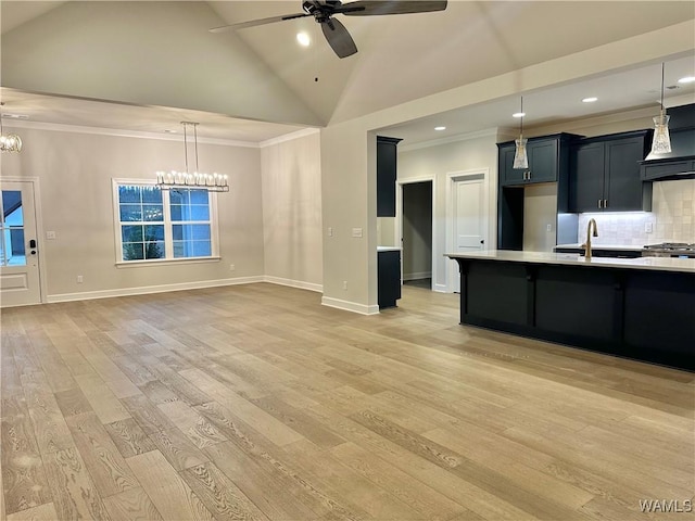 kitchen featuring backsplash, ventilation hood, ceiling fan with notable chandelier, sink, and decorative light fixtures