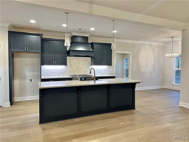 kitchen with hanging light fixtures, an island with sink, a chandelier, custom range hood, and light wood-type flooring