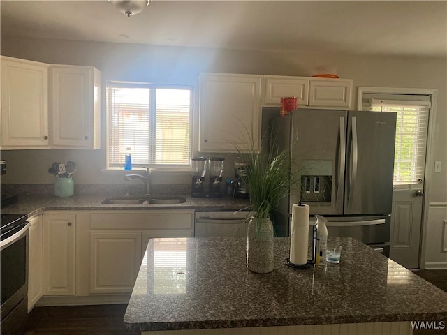 kitchen featuring dark stone counters, white cabinets, sink, a wealth of natural light, and appliances with stainless steel finishes