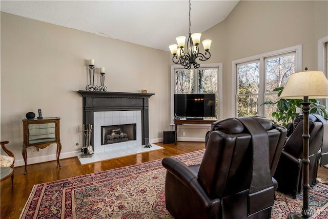 living room with a fireplace, wood finished floors, baseboards, and vaulted ceiling