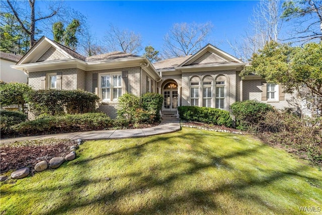 view of front of house featuring brick siding, french doors, and a front yard