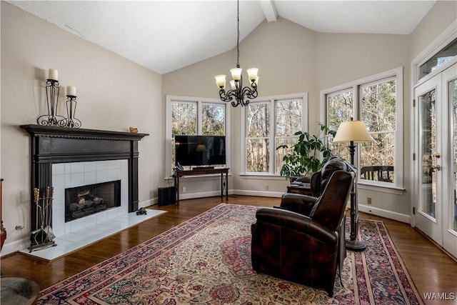 living area with vaulted ceiling with beams, baseboards, a fireplace, wood finished floors, and a notable chandelier