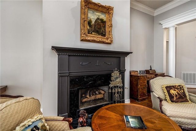 sitting room with visible vents, wood finished floors, decorative columns, crown molding, and a premium fireplace