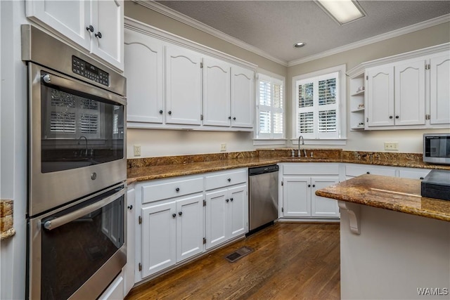 kitchen featuring dark wood finished floors, ornamental molding, appliances with stainless steel finishes, white cabinetry, and a sink