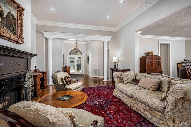 living area featuring visible vents, wood finished floors, a fireplace, and ornate columns